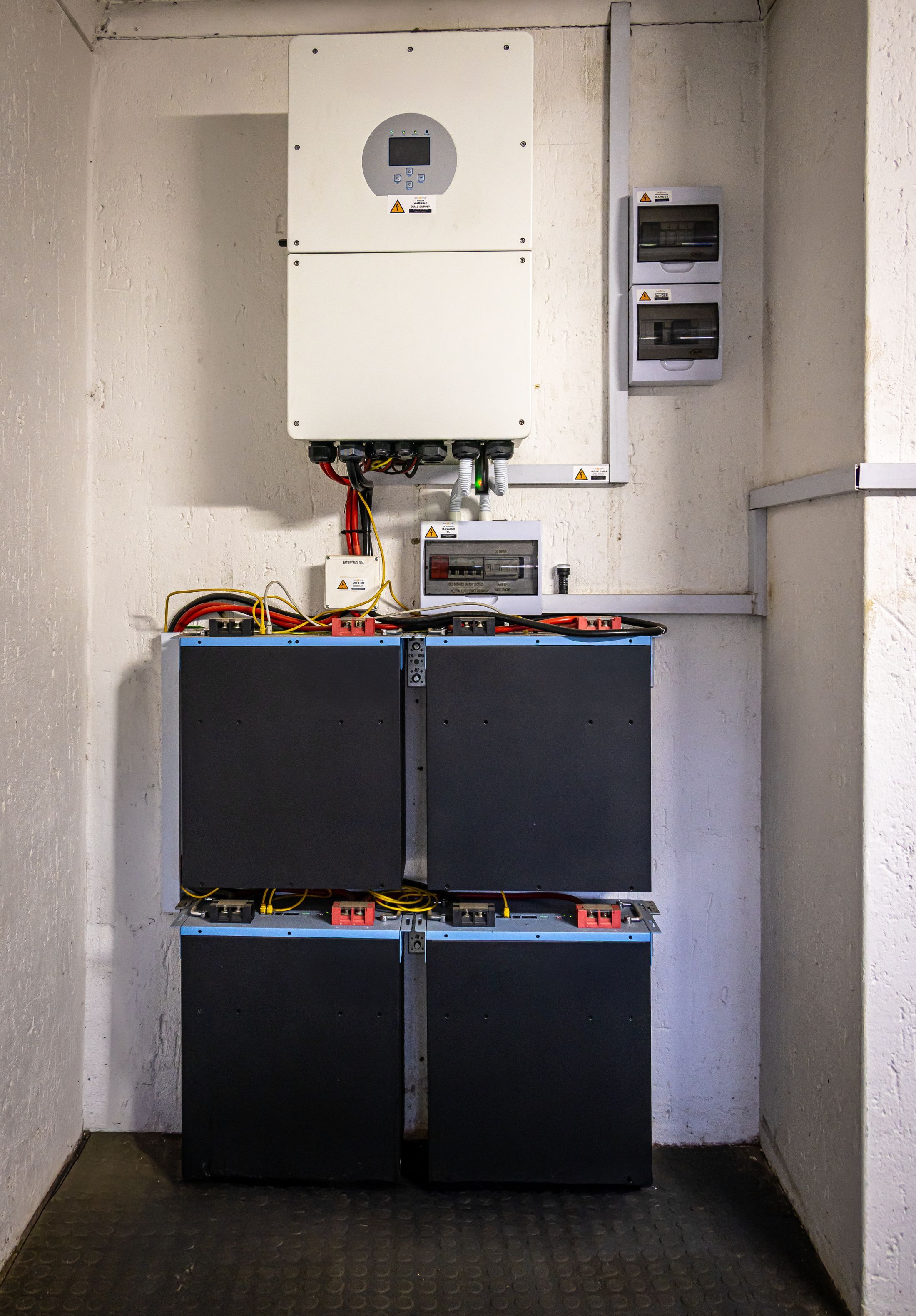 Modules de batterie noirs empilés sous un onduleur fixé au mur