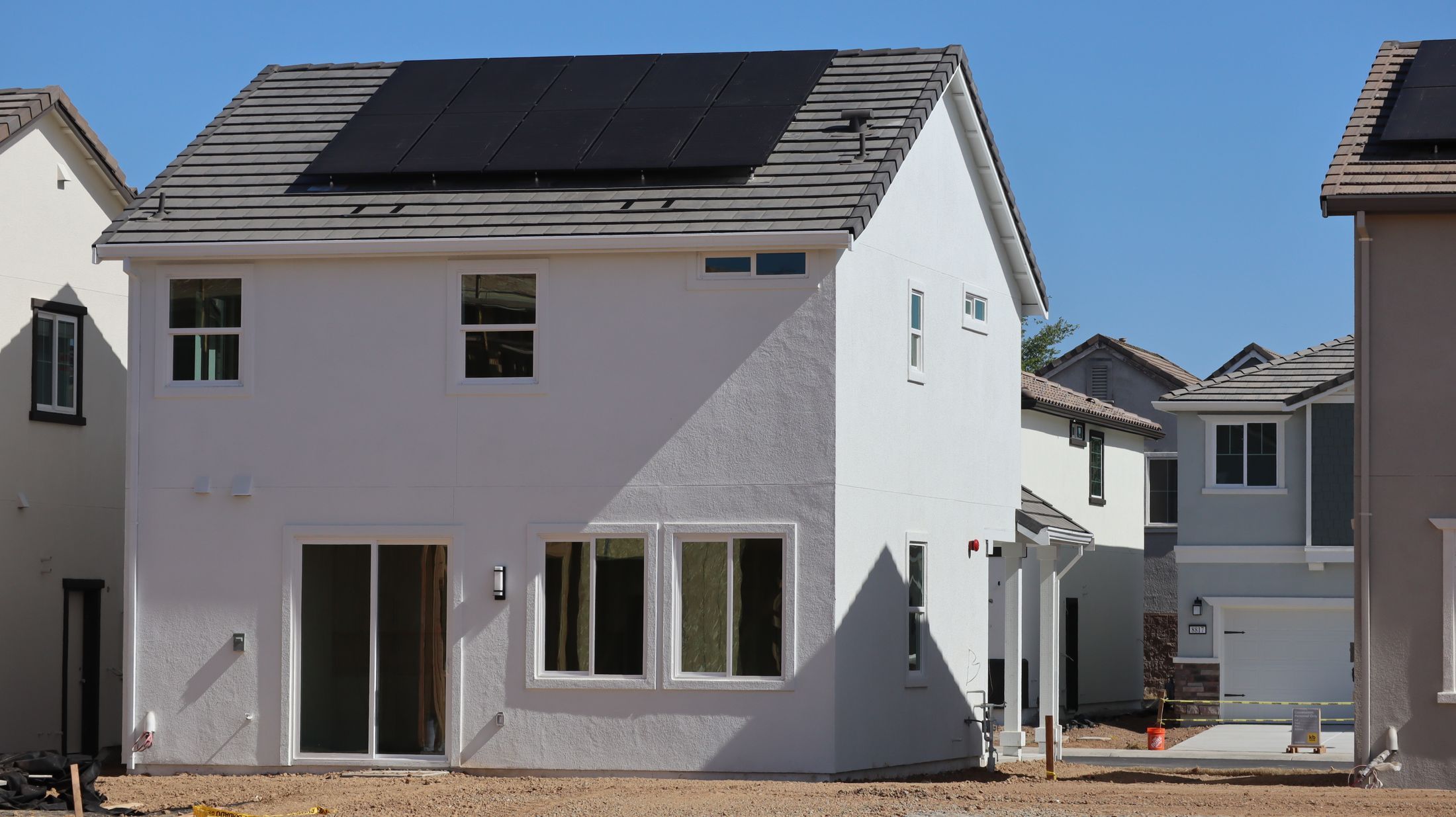 Maison blanche à toit sombre avec modules photovoltaïques, ciel bleu