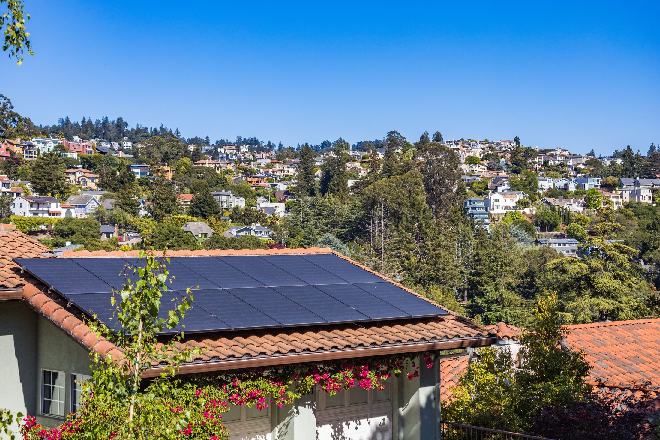 Maison avec modules photovoltaïques sur le toit, coteau boisé en arrière-plan