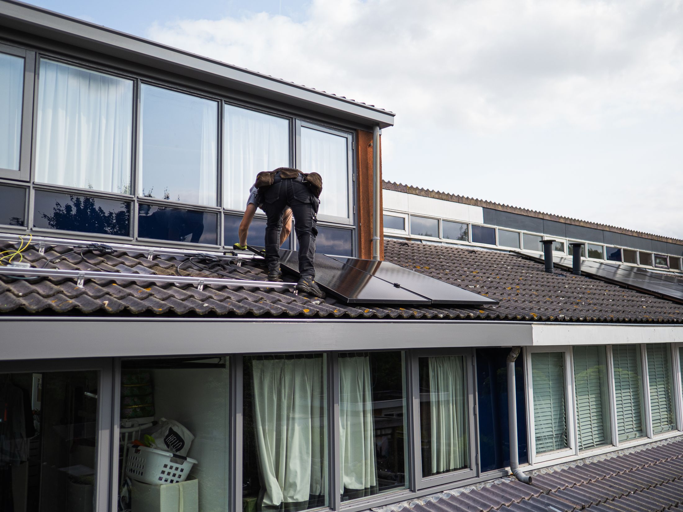 Technicien agenouillé sur une toiture-terrasse en train de poser des modules