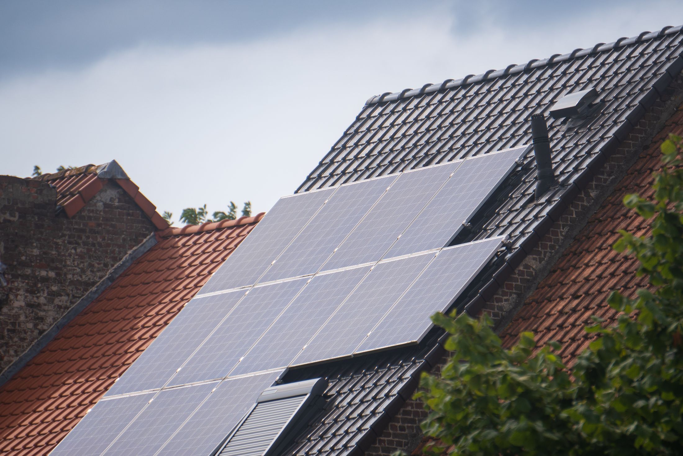 Modules photovoltaïques sur un toit d’ardoise sombre, ciel gris
