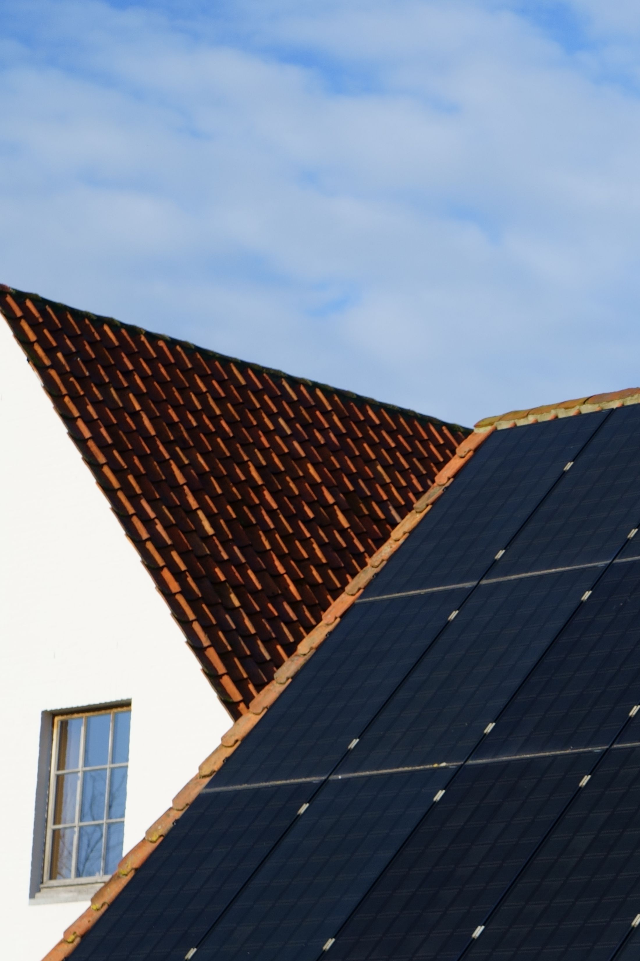 Détail de modules photovoltaïques noirs sur des tuiles, à la jonction de deux pans